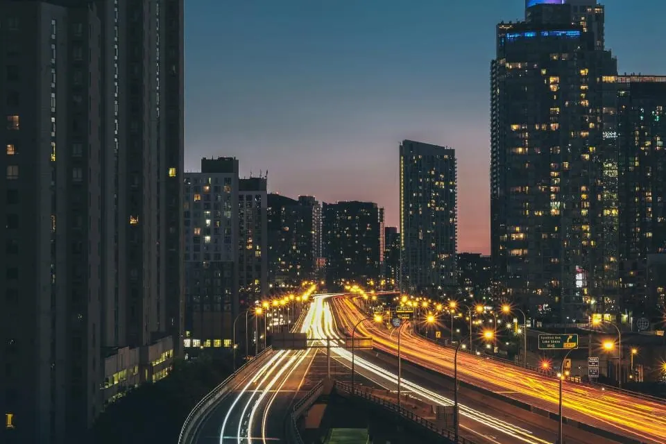 夜晚的城市街景，远处高楼亮着灯，近处街道上有车辆驶过