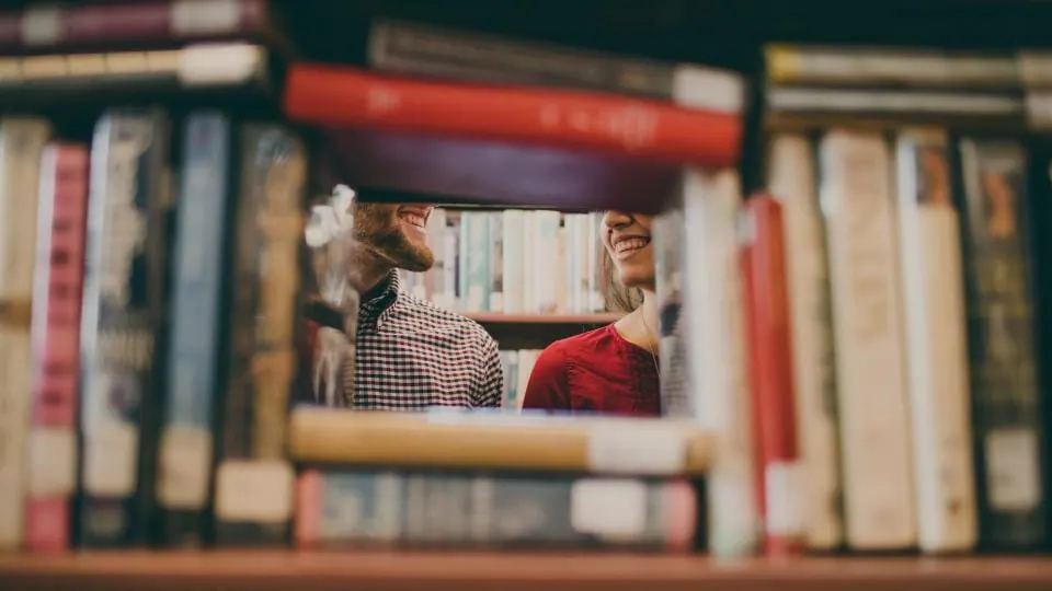 شخصان بين أرفف الكتب داخل مكتبة هادئة