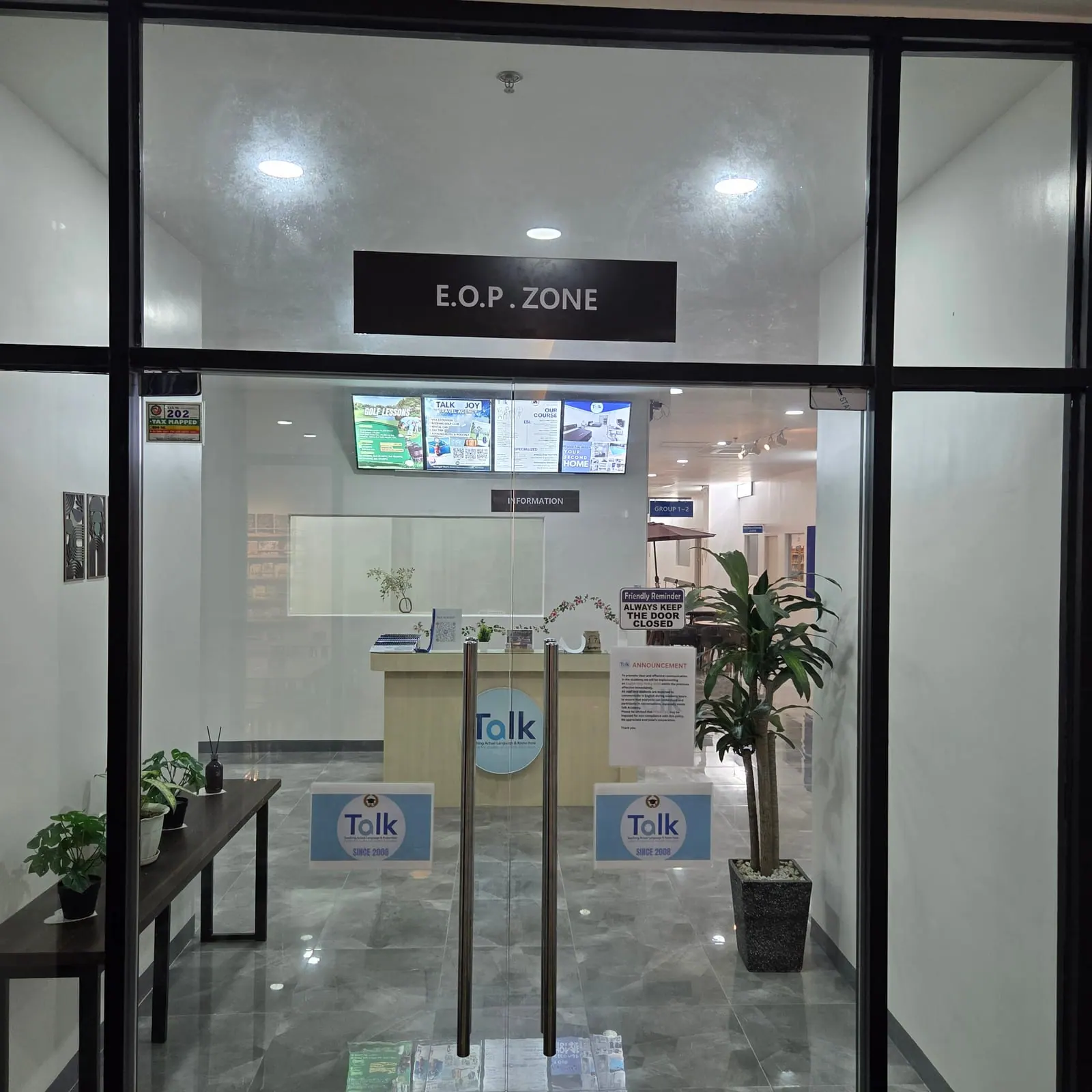 玻璃门内的学校前台与资讯柜台,门上方挂着 E.O.P. ZONE 标示牌