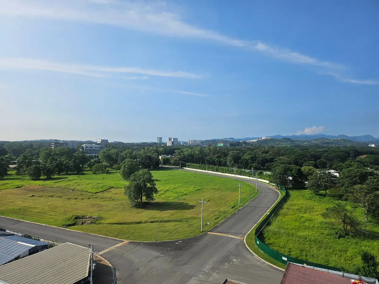 広い芝生と整備された道路、遠くに高層ビルと山並みが見えるクラーク経済特区の街並み