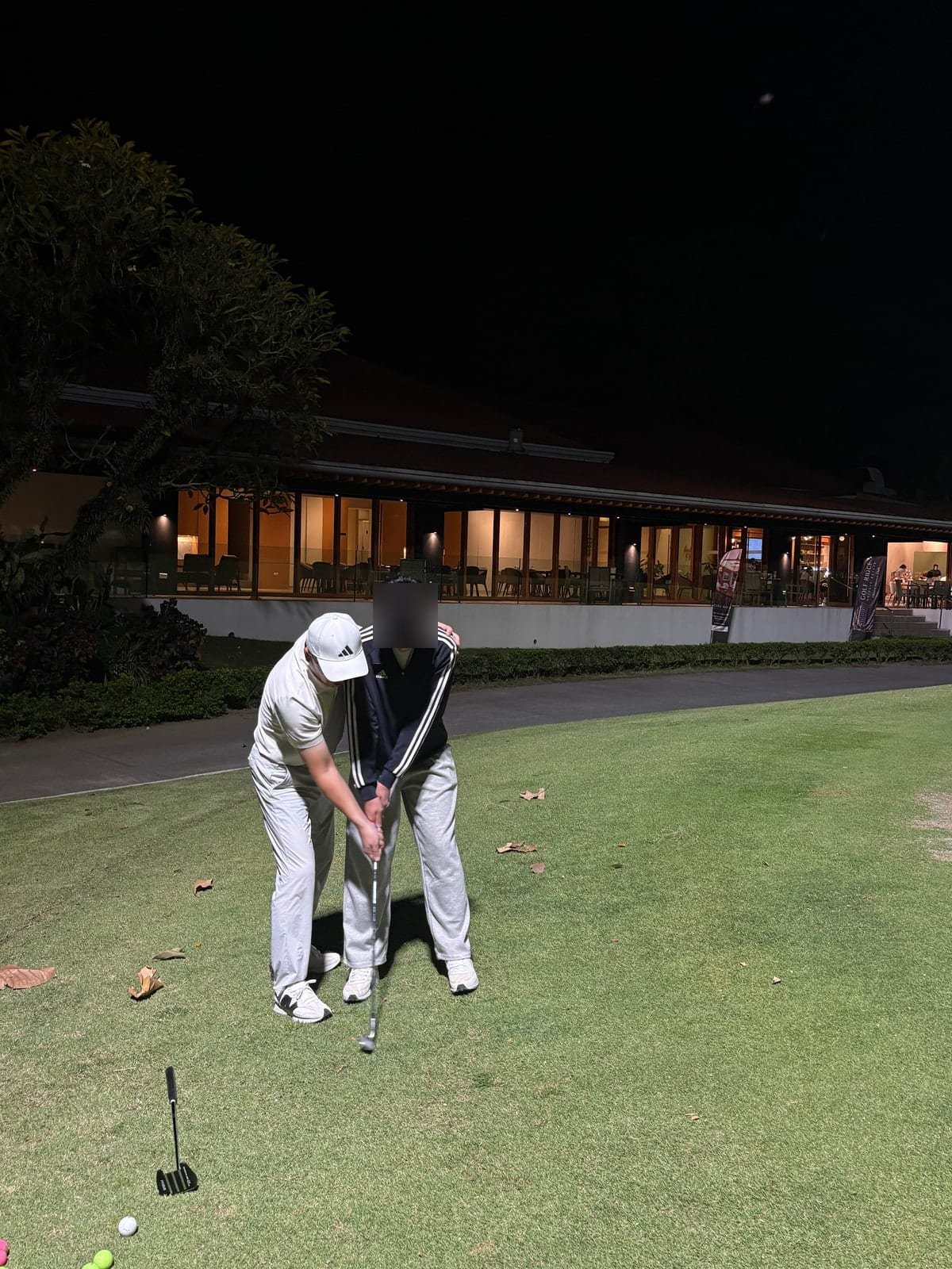 Hands-on grip coaching during an evening putting lesson