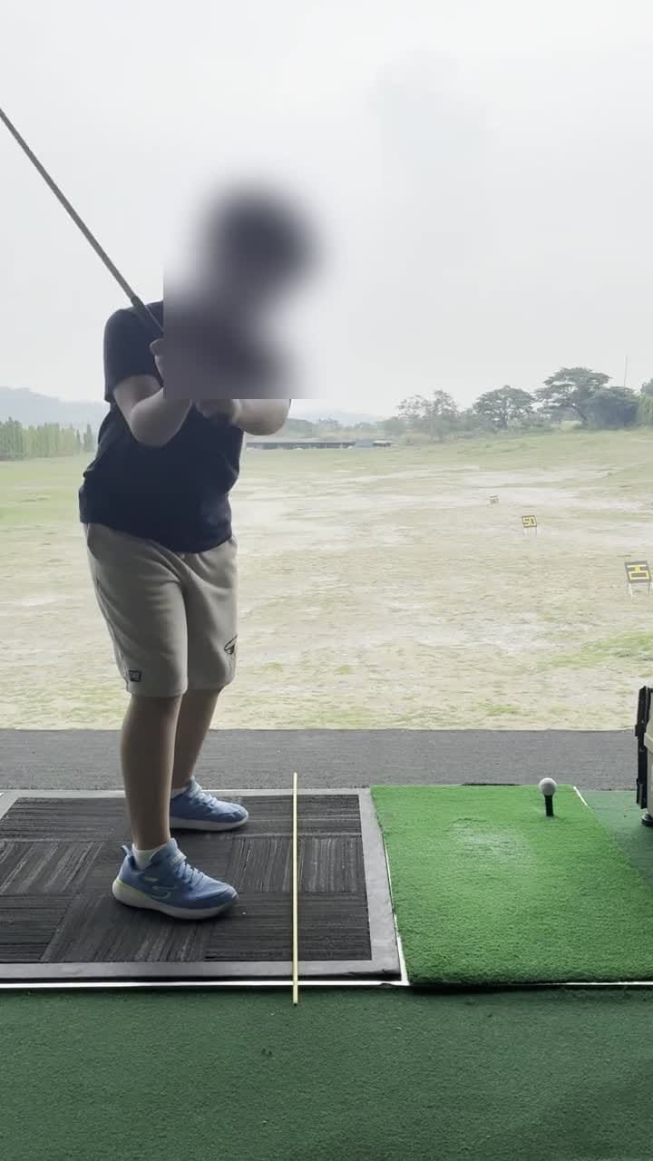 Junior student practising a full swing at the driving range
