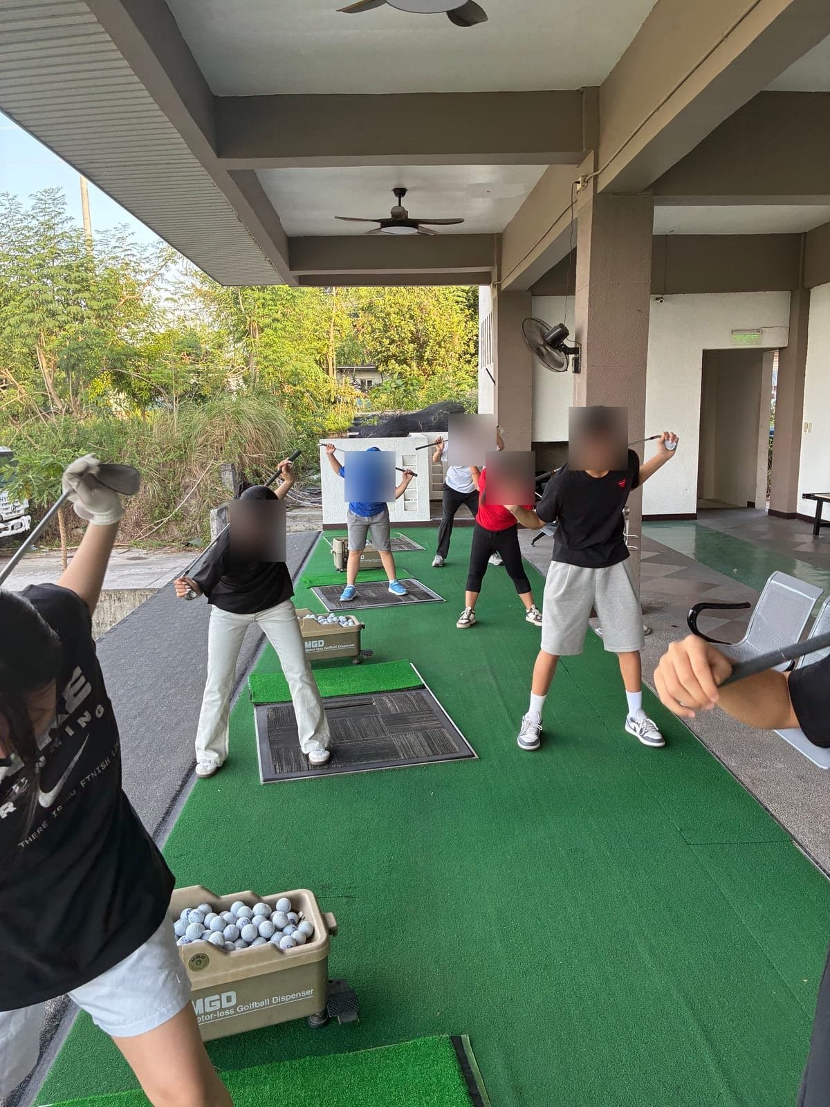 Students warming up with clubs before a golf lesson