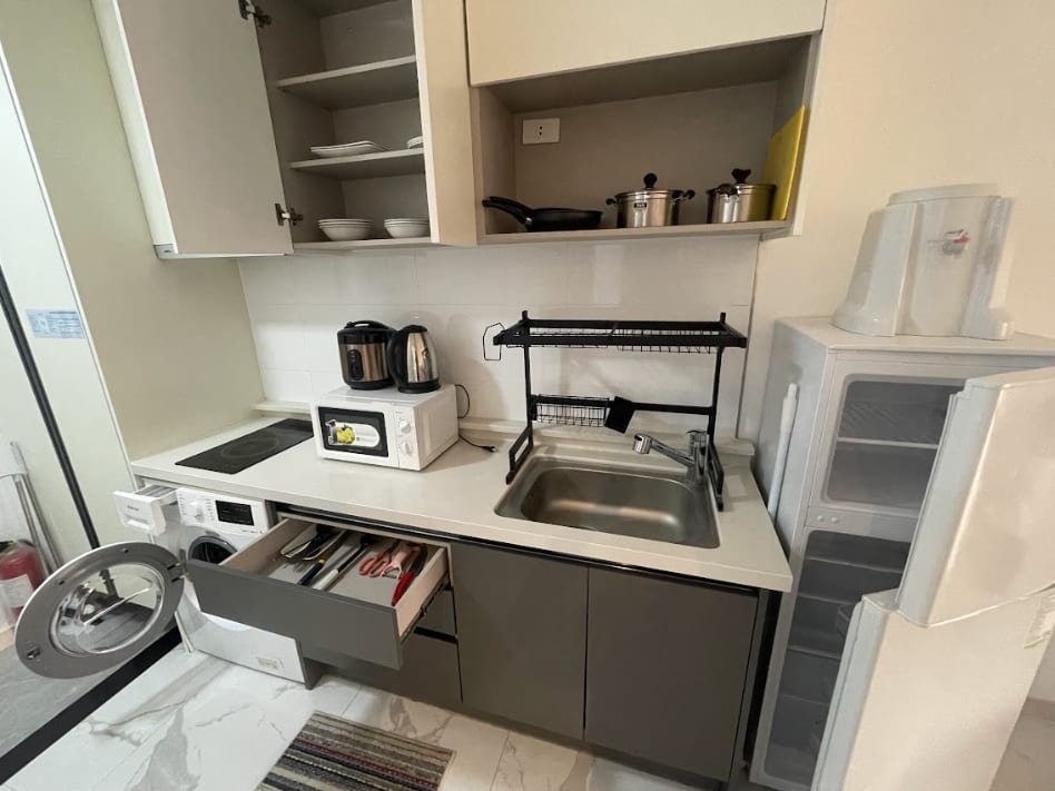 The dorm kitchen: induction hob, sink, microwave, washing machine and storage cupboards