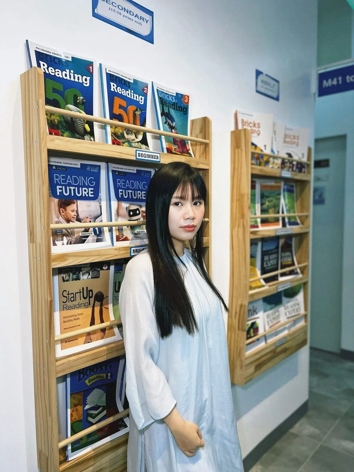 학원 교재 서가 옆에 선 응옥타오