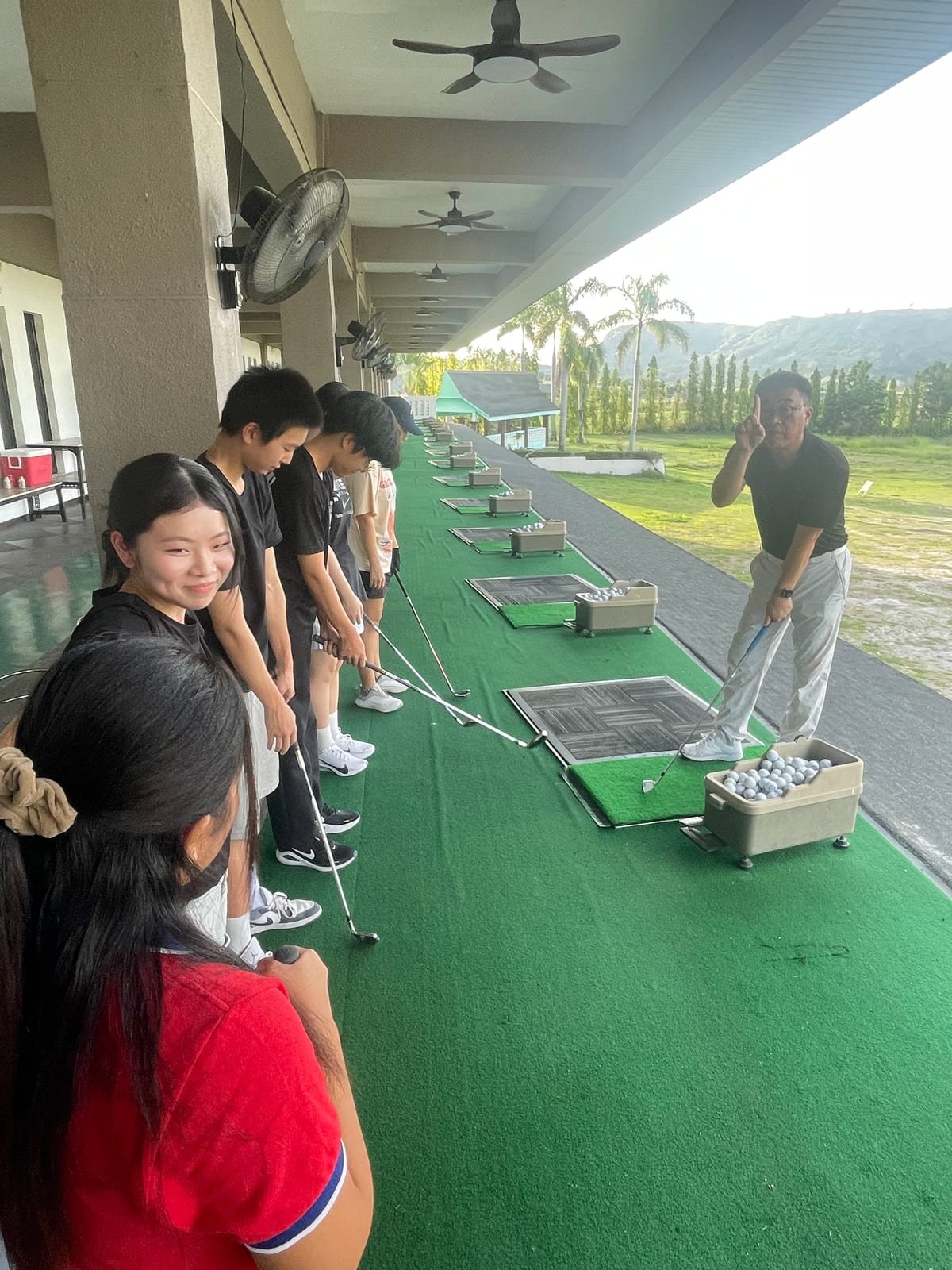 Students lined up at bays on a golf driving range