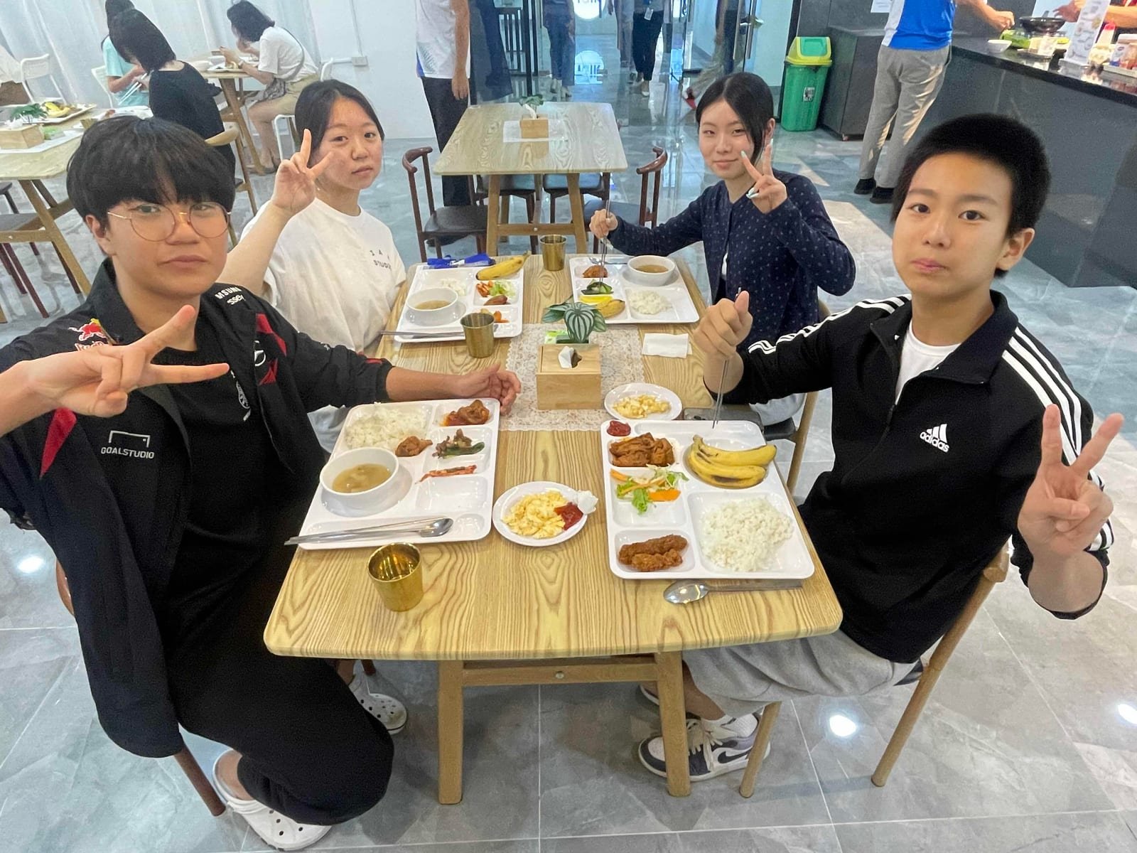 Students at a canteen table with loaded trays in front of them